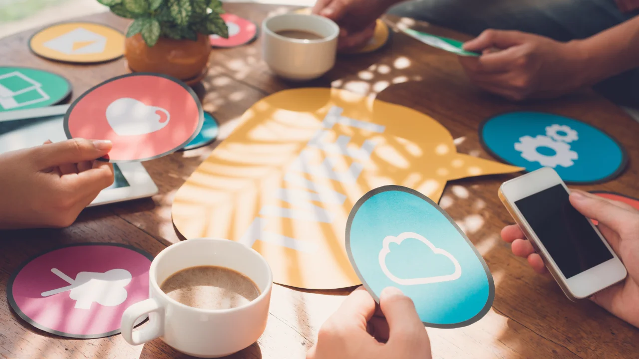 Personas planificando estrategias de redes sociales con iconos digitales sobre una mesa.